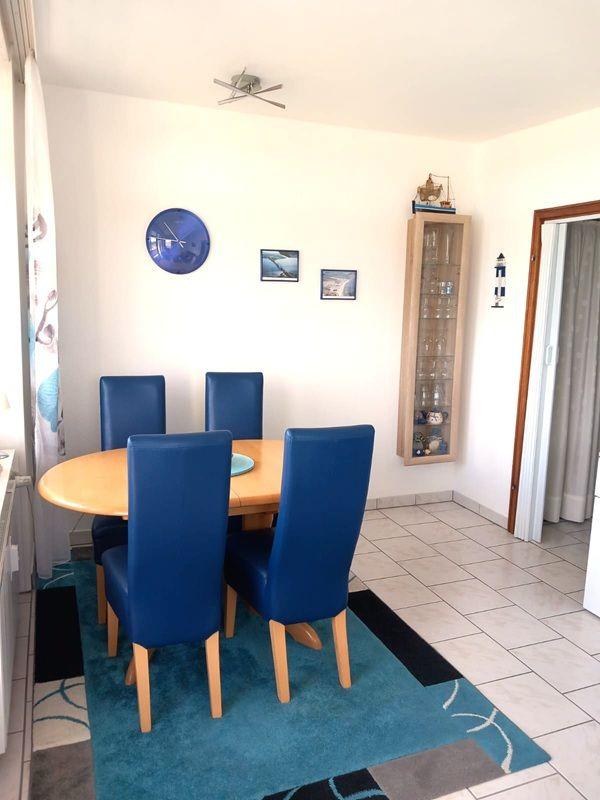 Esszimmer mit runder Tisch, blauen Stühlen und Wanduhr
