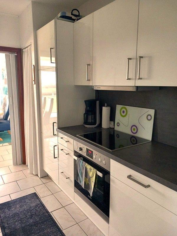 Küche mit weißen Schränken, Induktionskochfeld und integriertem Backofen.