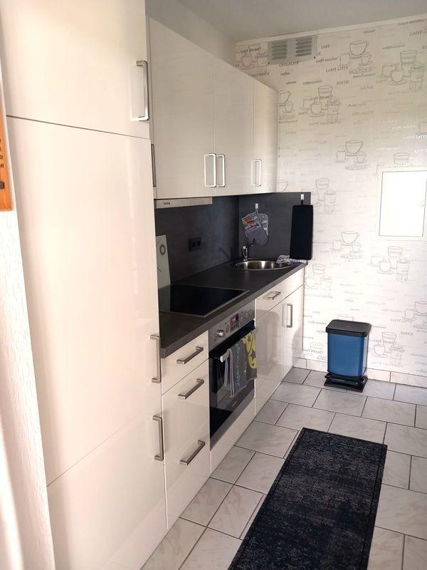 Küche mit weißen Schränken, schwarzer Arbeitsplatte und Mosaikwand.