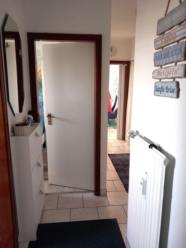 Eingangsbereich mit Spiegel, Schrank und Tür zu Wohnbereich.