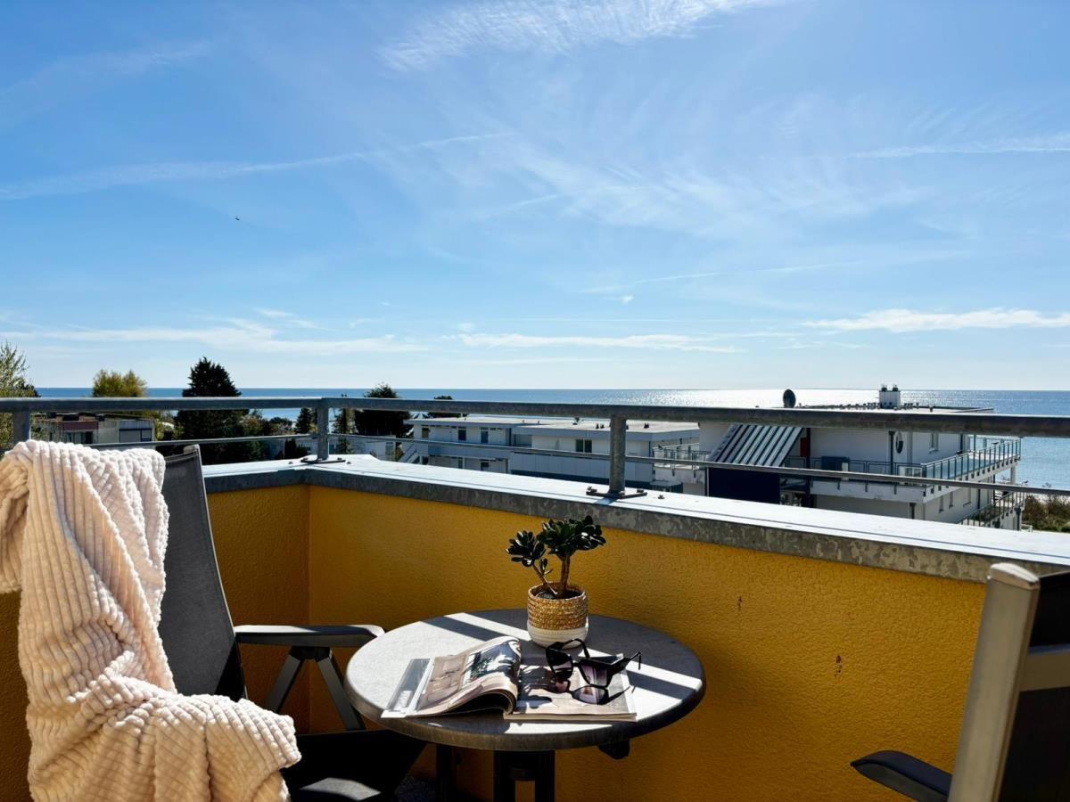Terrasse mit Blick auf das Meer und Gebäude. Tisch, Stuhl, Pflanze und Zeitschrift.