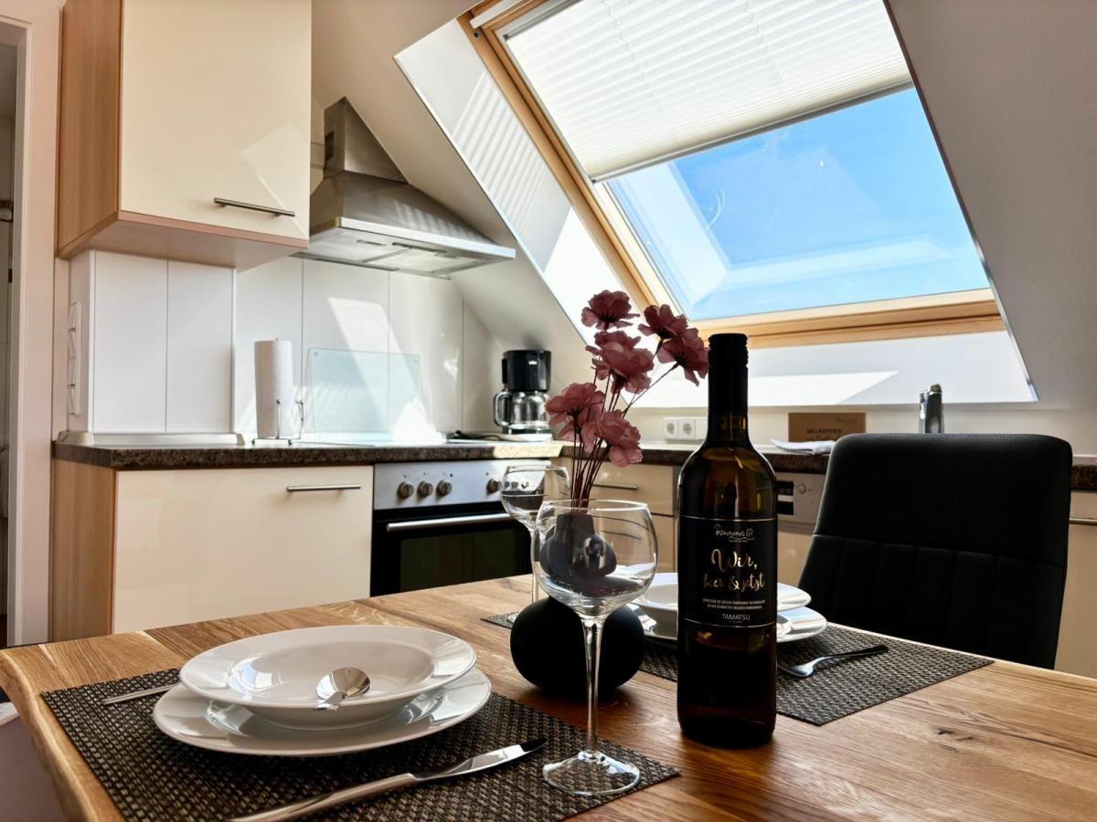 Essbereich mit Tisch, Stühlen und Weinflasche unter Dachfenster.
