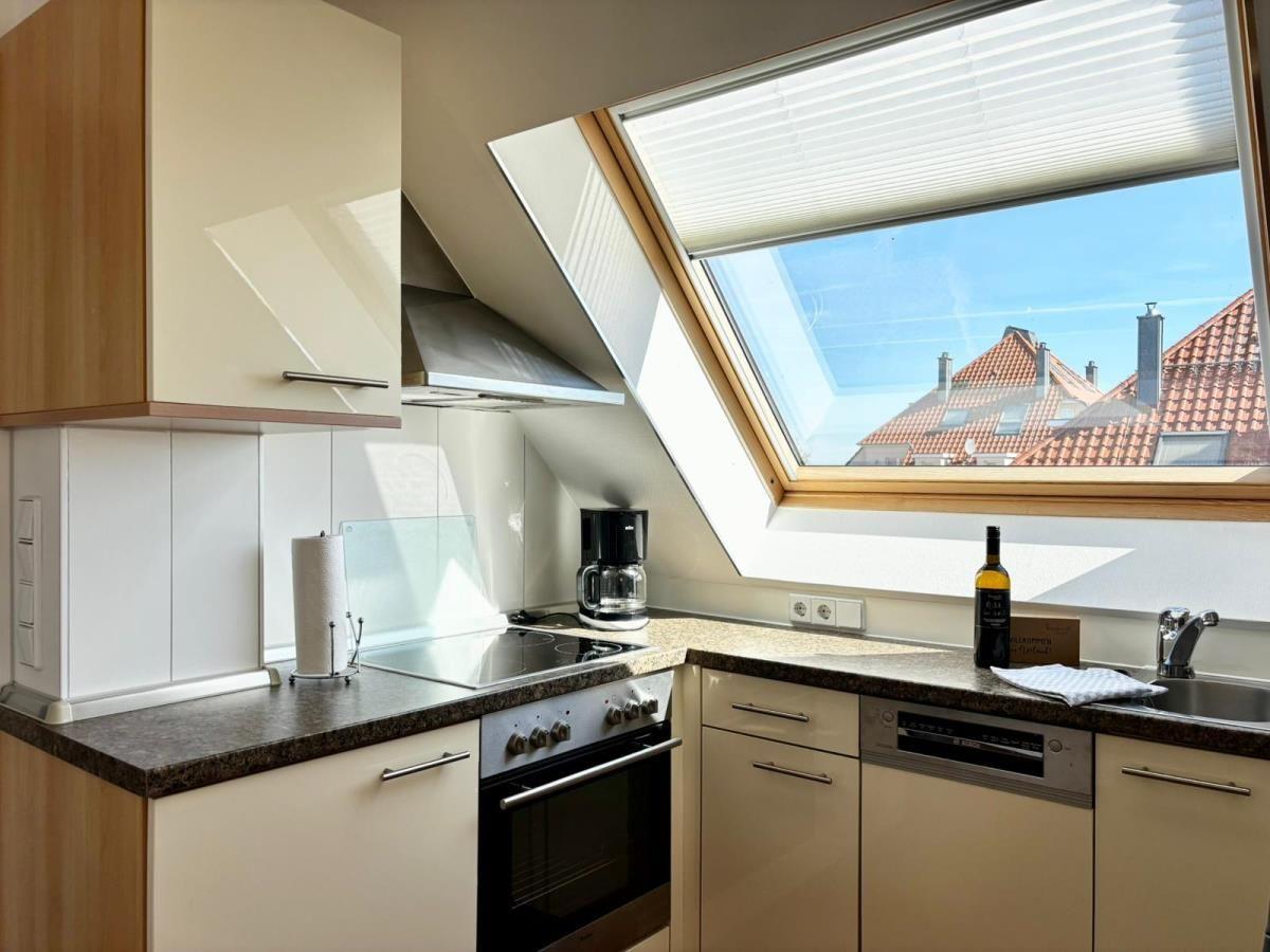 Küche mit Dunstabzug, Herd und Dachfenster mit Blick auf Dächer.