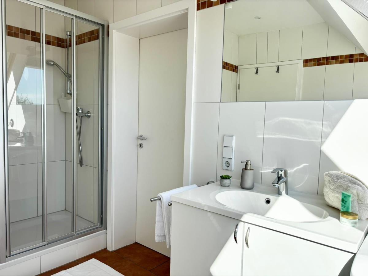 Badezimmer mit Dusche, Waschbecken und Spiegel