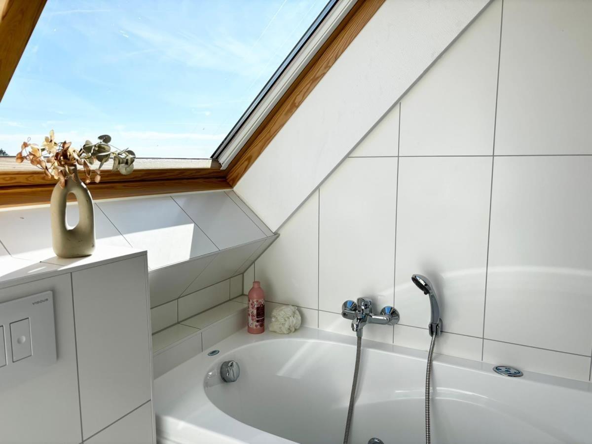 Bad mit Dusche und Dachfenster, weißer Fliesenwand und Waschbecken mit Vasen.