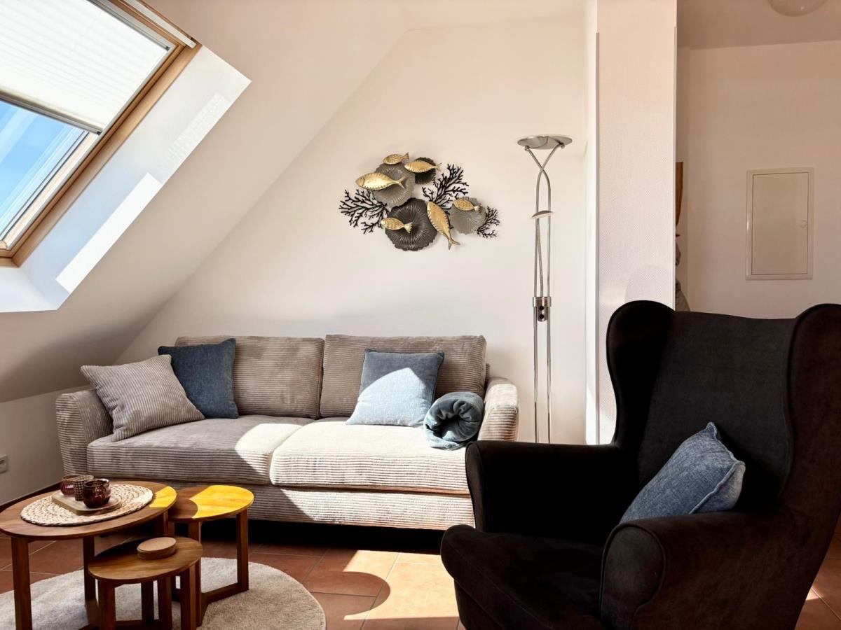 Wohnzimmer mit Sofa, Sessel und Dachfenster. Wanddekoration mit Fischen.
