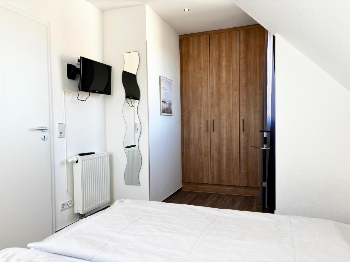 Schlafzimmer mit Bett, Kleiderschrank und Wandfernseher.