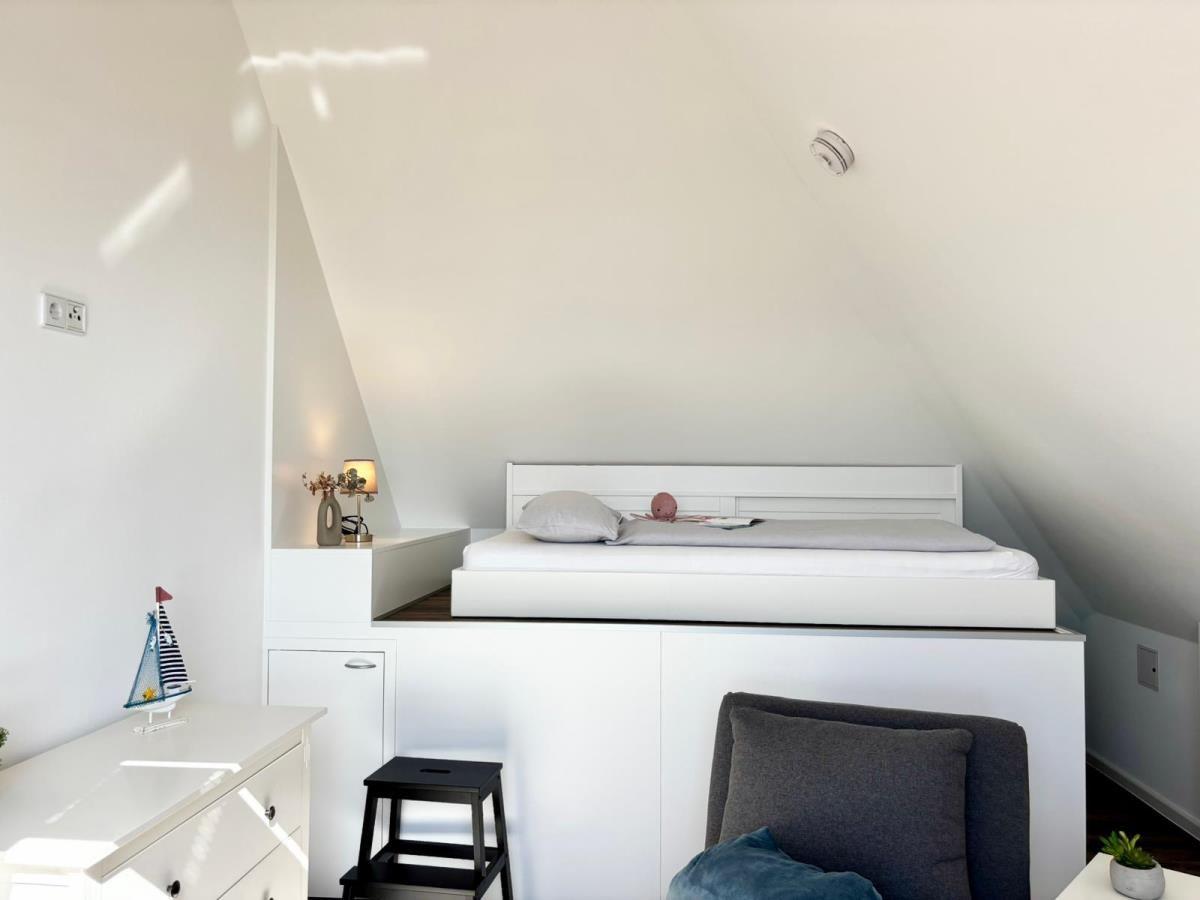Schlafzimmer mit Hochbett, Nachttisch und Stuhl unter schrägen Dachschrägen.