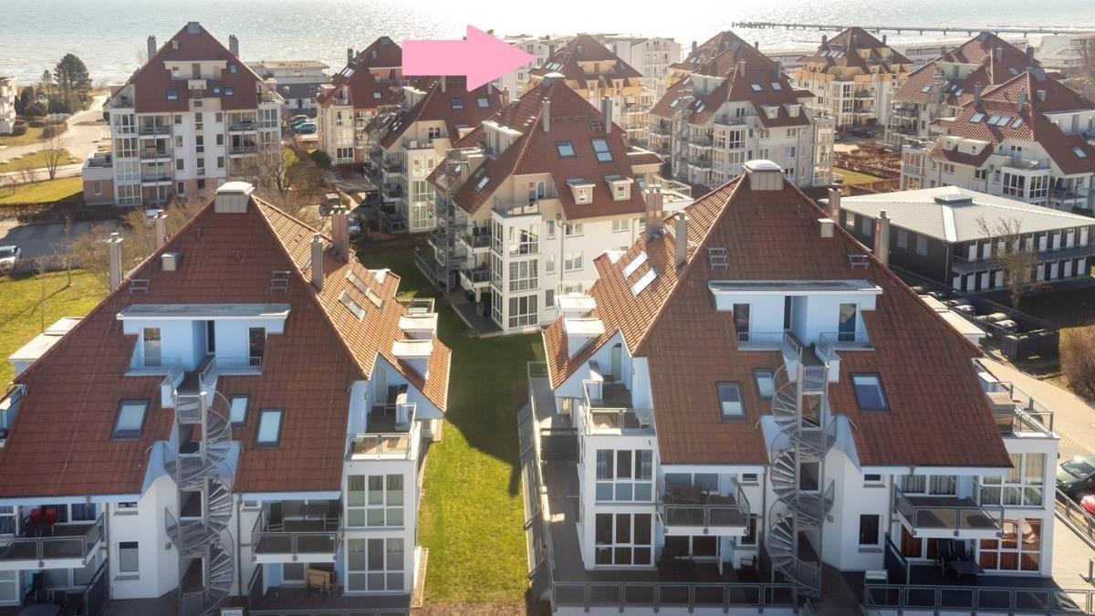 Hochwertige Ferienwohnungen mit roten Dächern und Balkonen direkt am Strand.