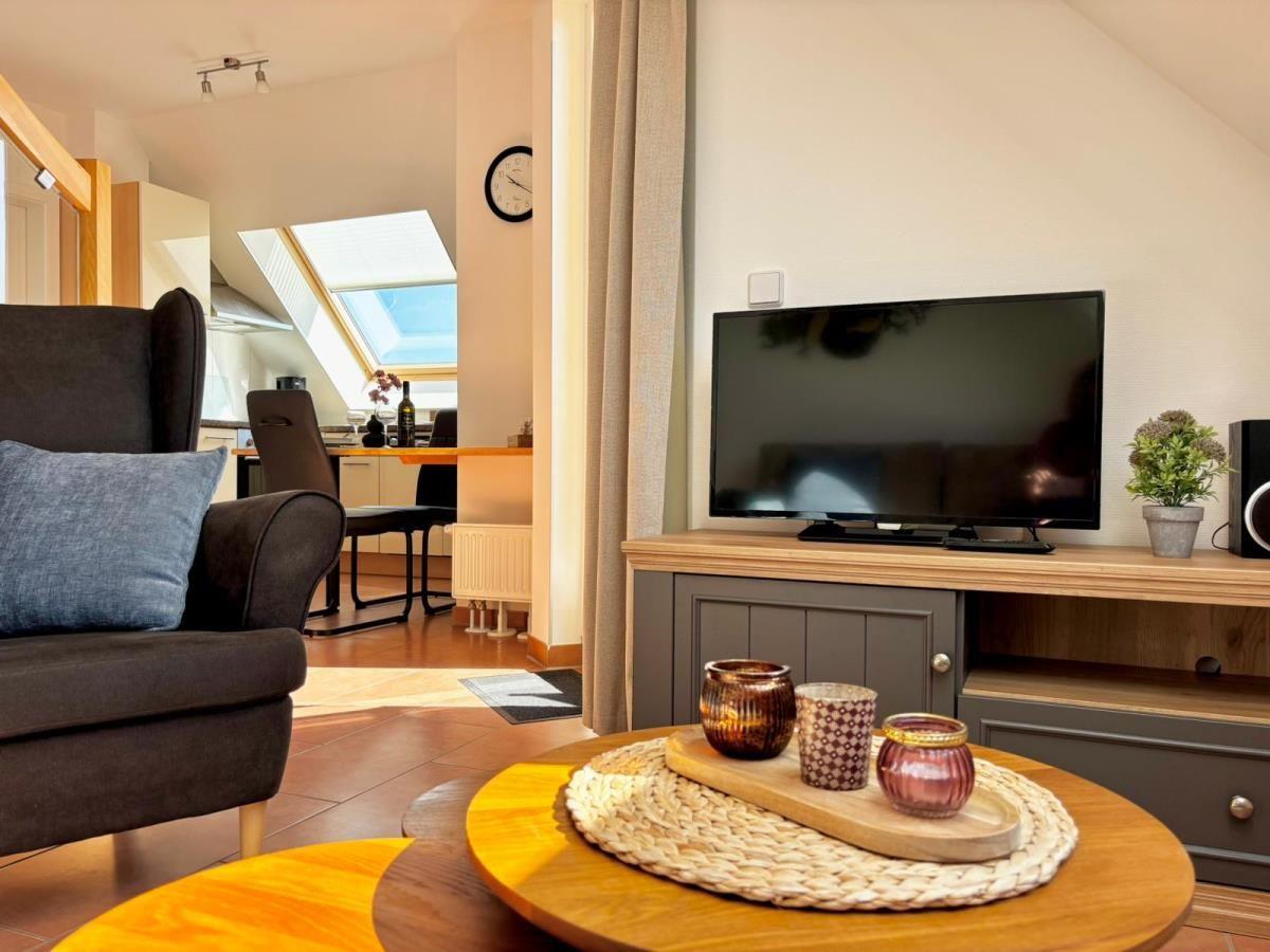 Wohnzimmer mit Fernseher, Couch und Esstisch im Hintergrund.
