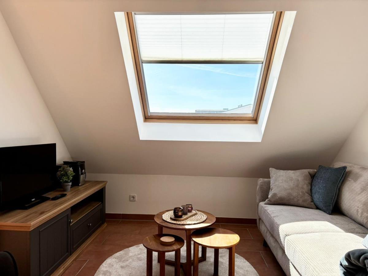 Dachgeschosswohnung mit Dachfenster, Sofa und Holztisch.