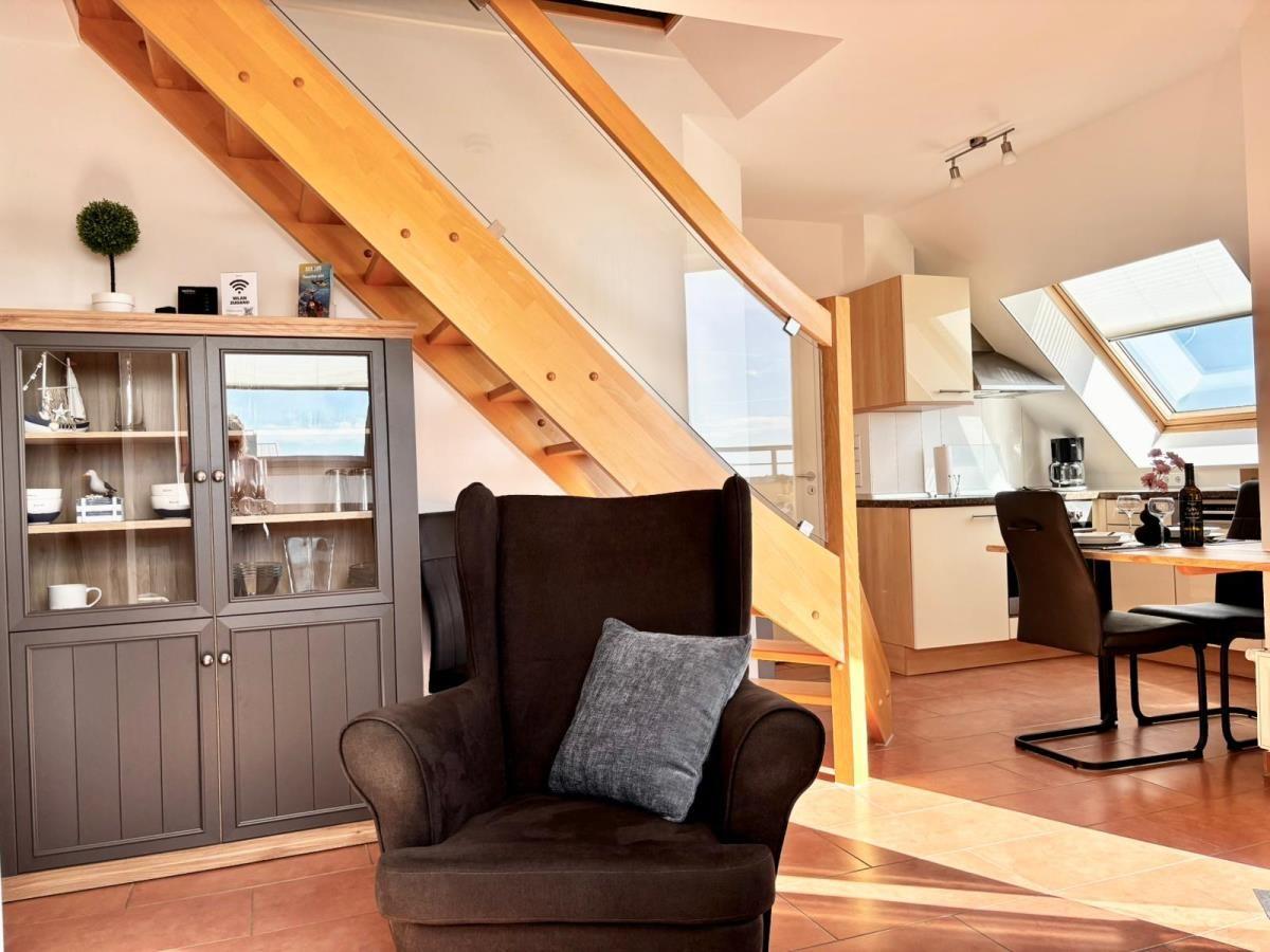 Ein Wohnbereich mit Sitzgelegenheit, Küchenbereich und Treppe unter Dachschrägen.