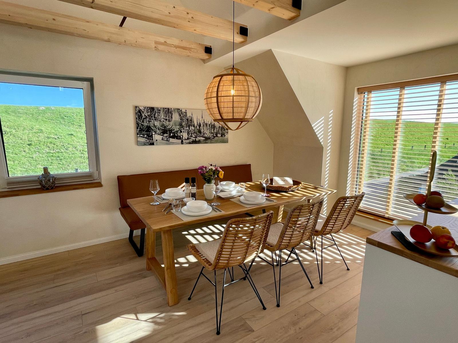 Esszimmer mit Holztisch, Stühlen und Blick auf grüne Landschaft.