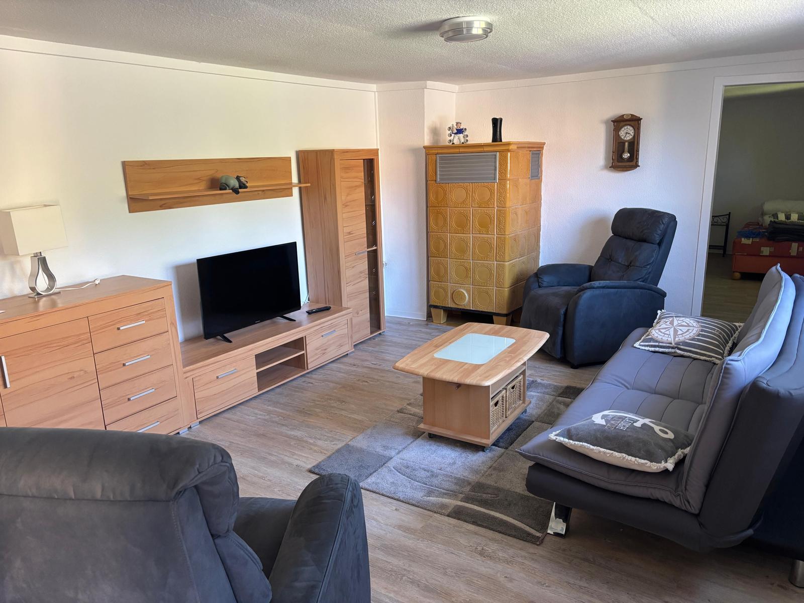 Wohnzimmer mit Sofa, Fernseher und Holzmöbeln.