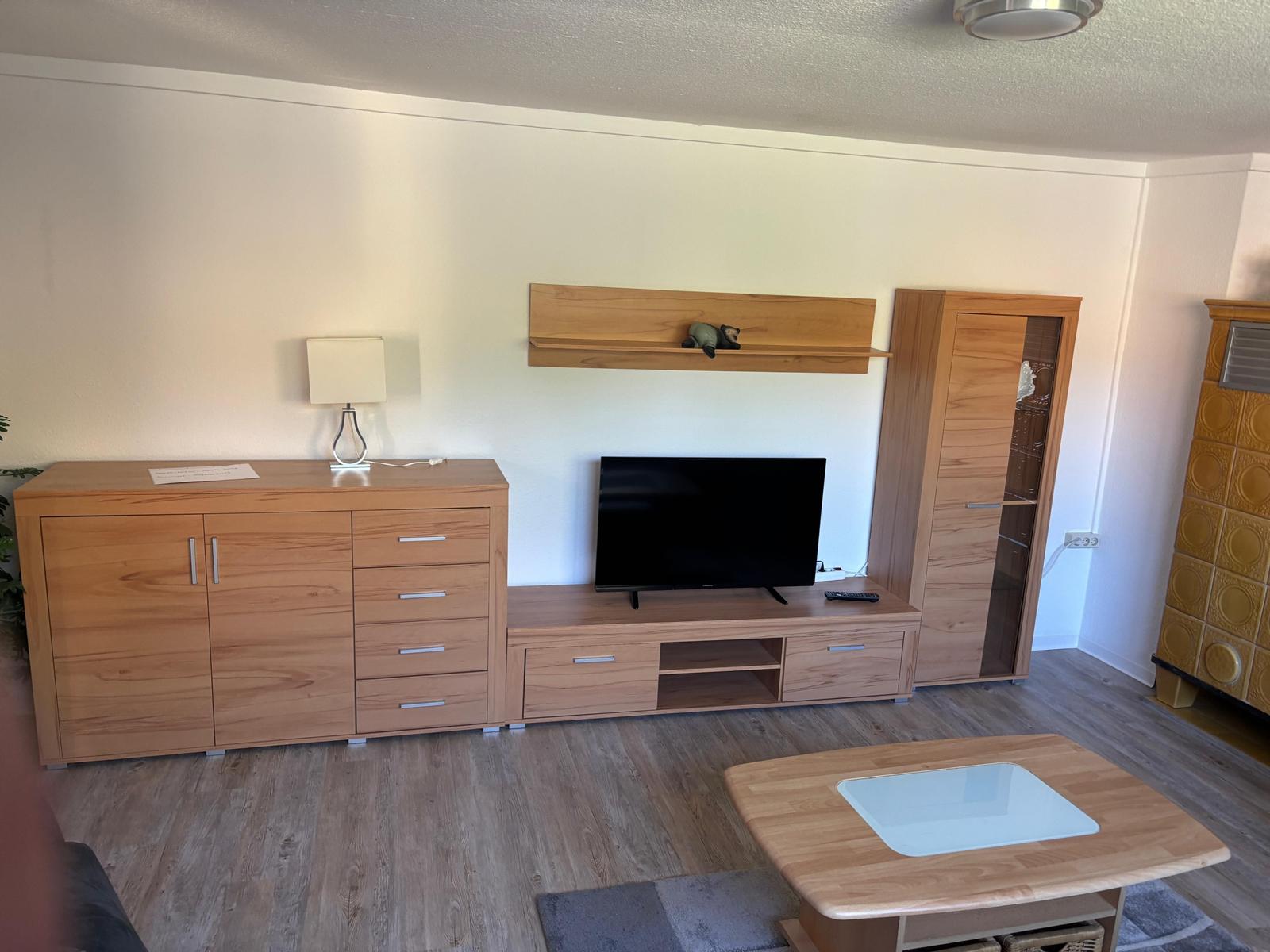 Wohnzimmer mit Holzmöbeln, Fernseher und Couchtisch.