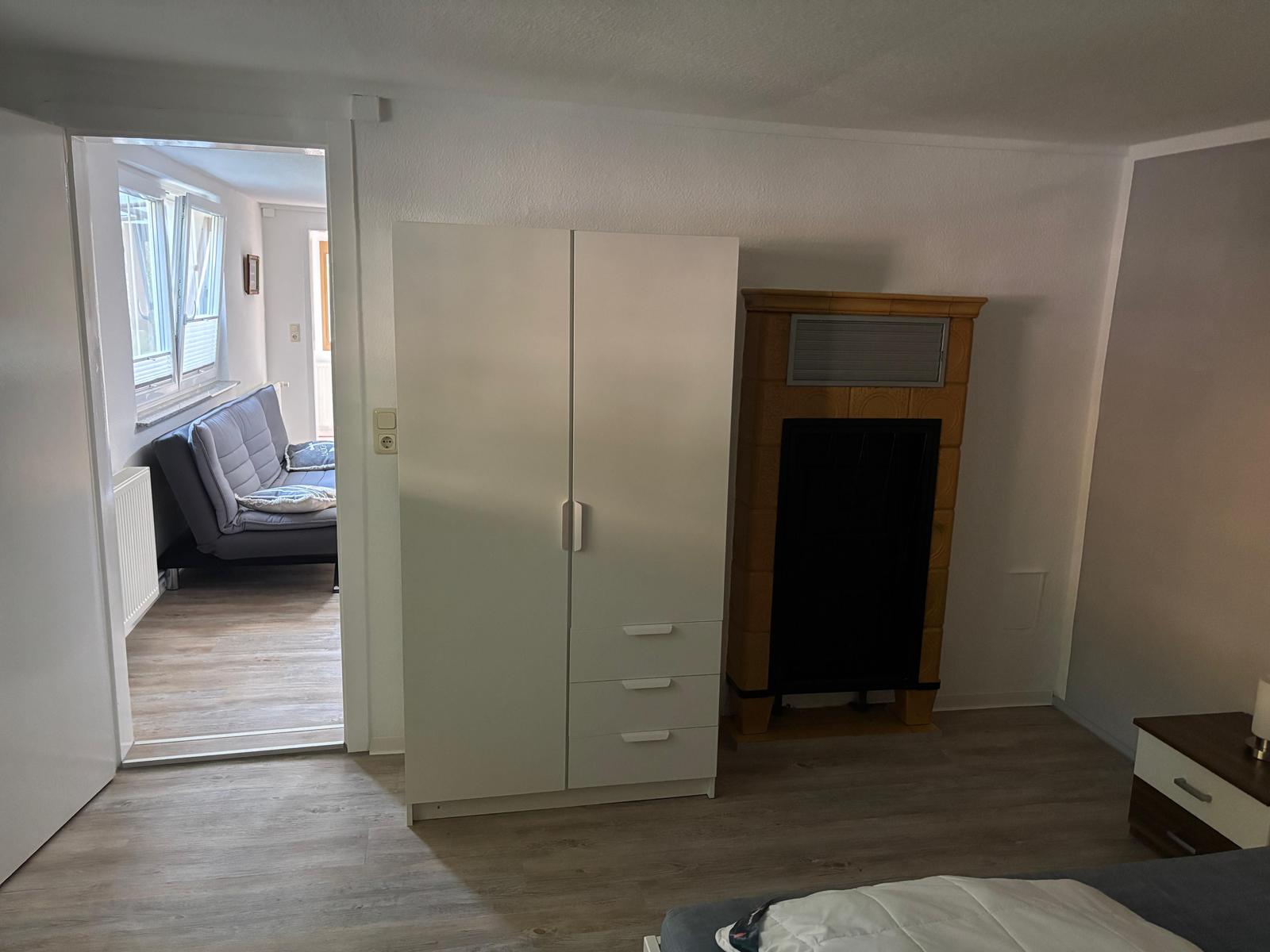 Schlafzimmer mit Kleiderschrank und Kamin, Blick in Wohnbereich mit Sofa.
