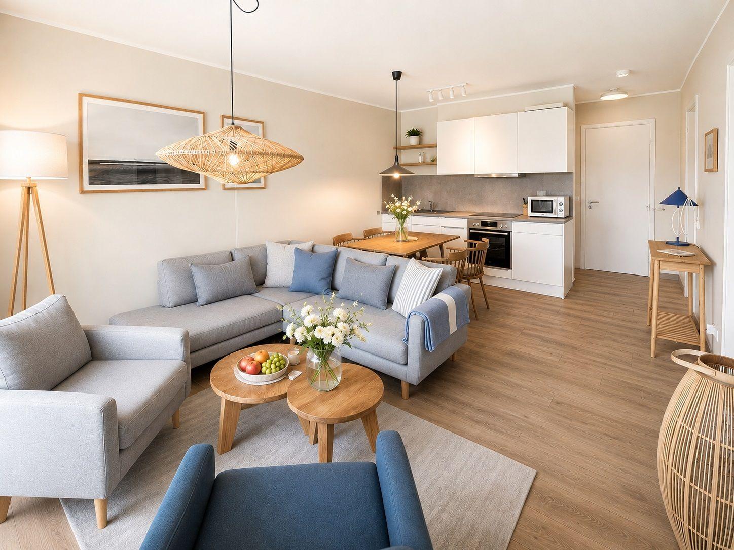 Wohnzimmer mit Sofa, Couchtisch und Küchenbereich mit weißen Schränken.