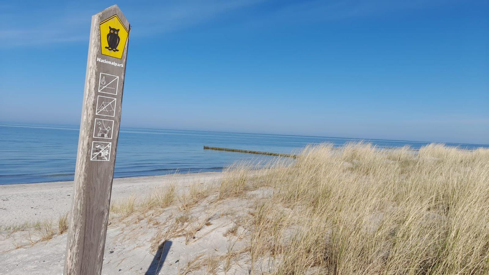 Nationalpark-Schild an Strand mit Dünen und Meer