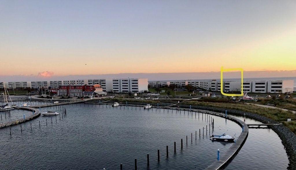 Hafen mit Booten und modernen Gebäuden bei Sonnenuntergang.