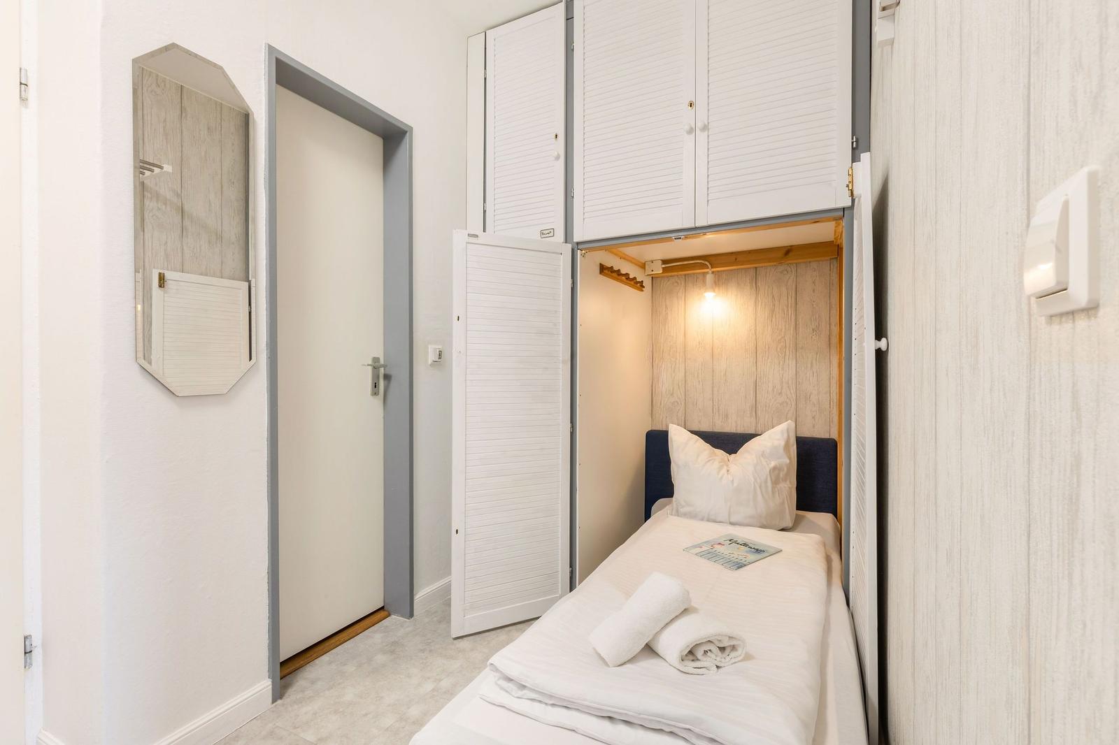 Schlafzimmer mit Bett, Schrank und Spiegel an der Wand.