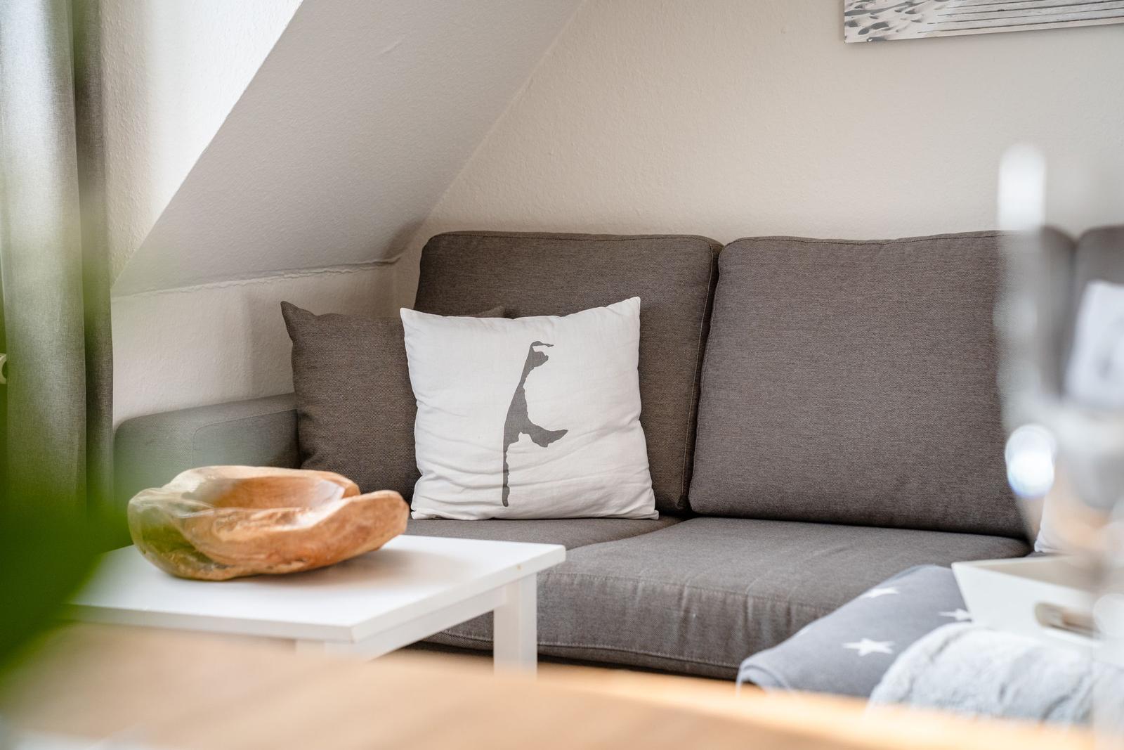 Gray sofa with cushions under sloped ceiling