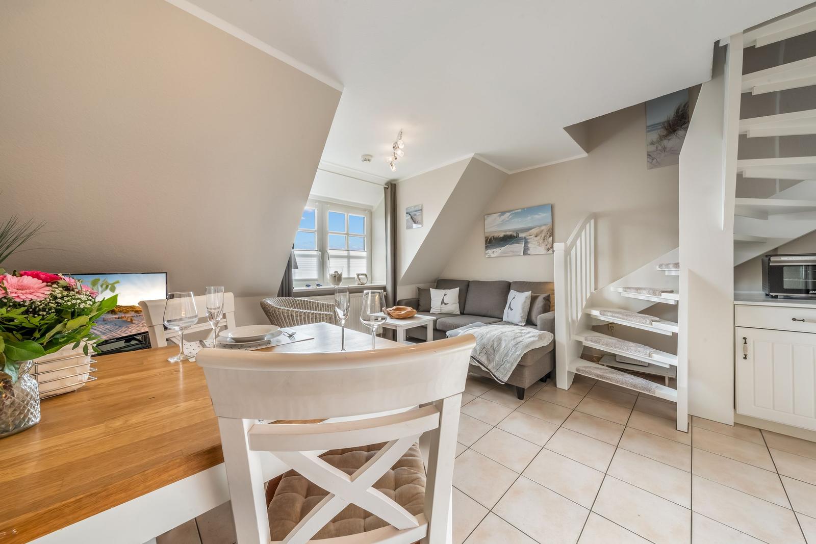 Dining area with table, chairs, and view of living area with sofa and staircase.