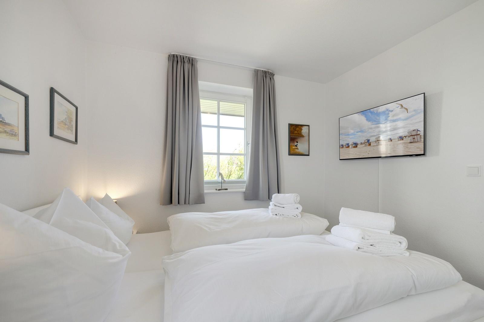 Zimmer mit Doppelbett, Fenster, TV und Handtüchern.
