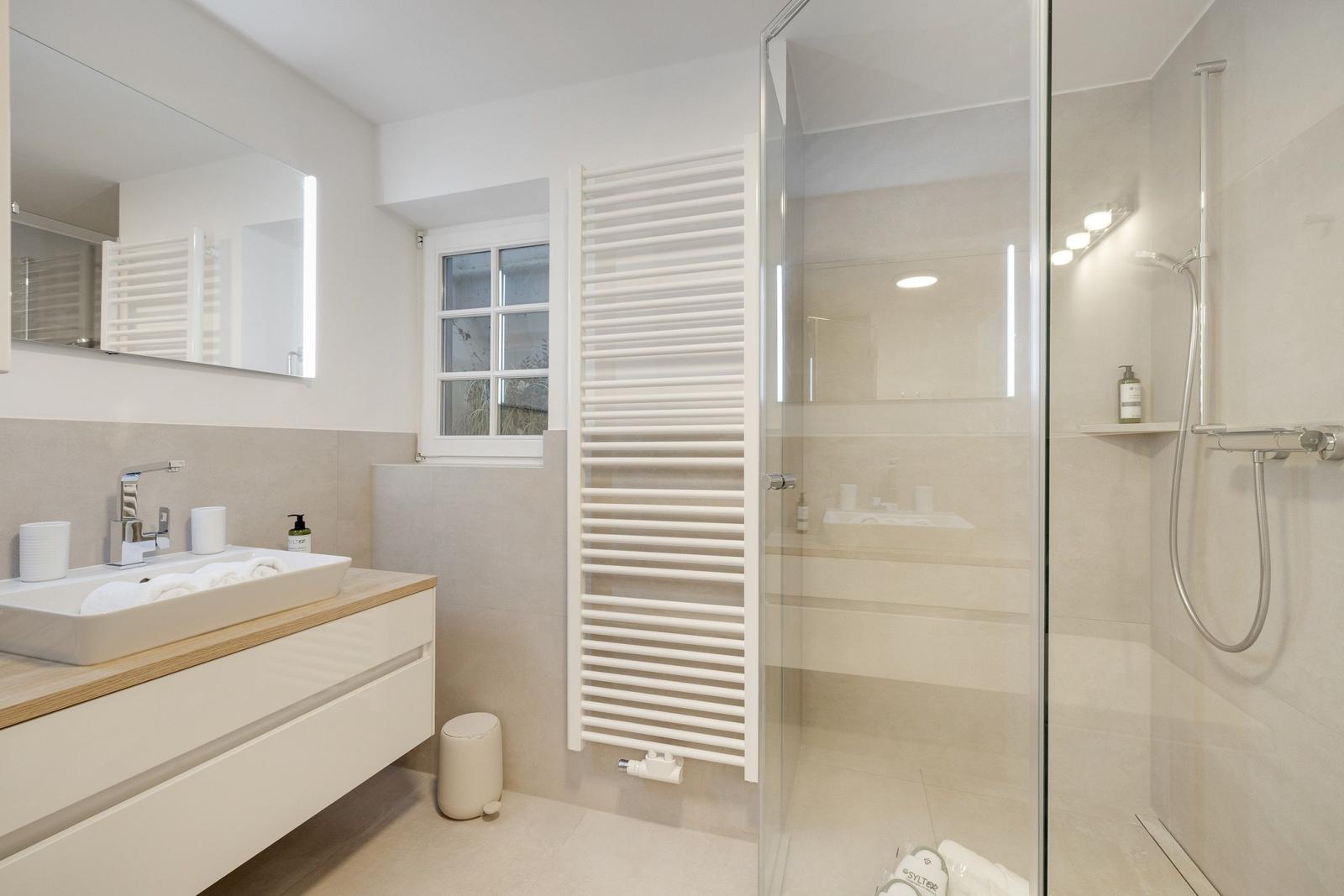 Badezimmer mit Dusche, Waschbecken und Heizkörper