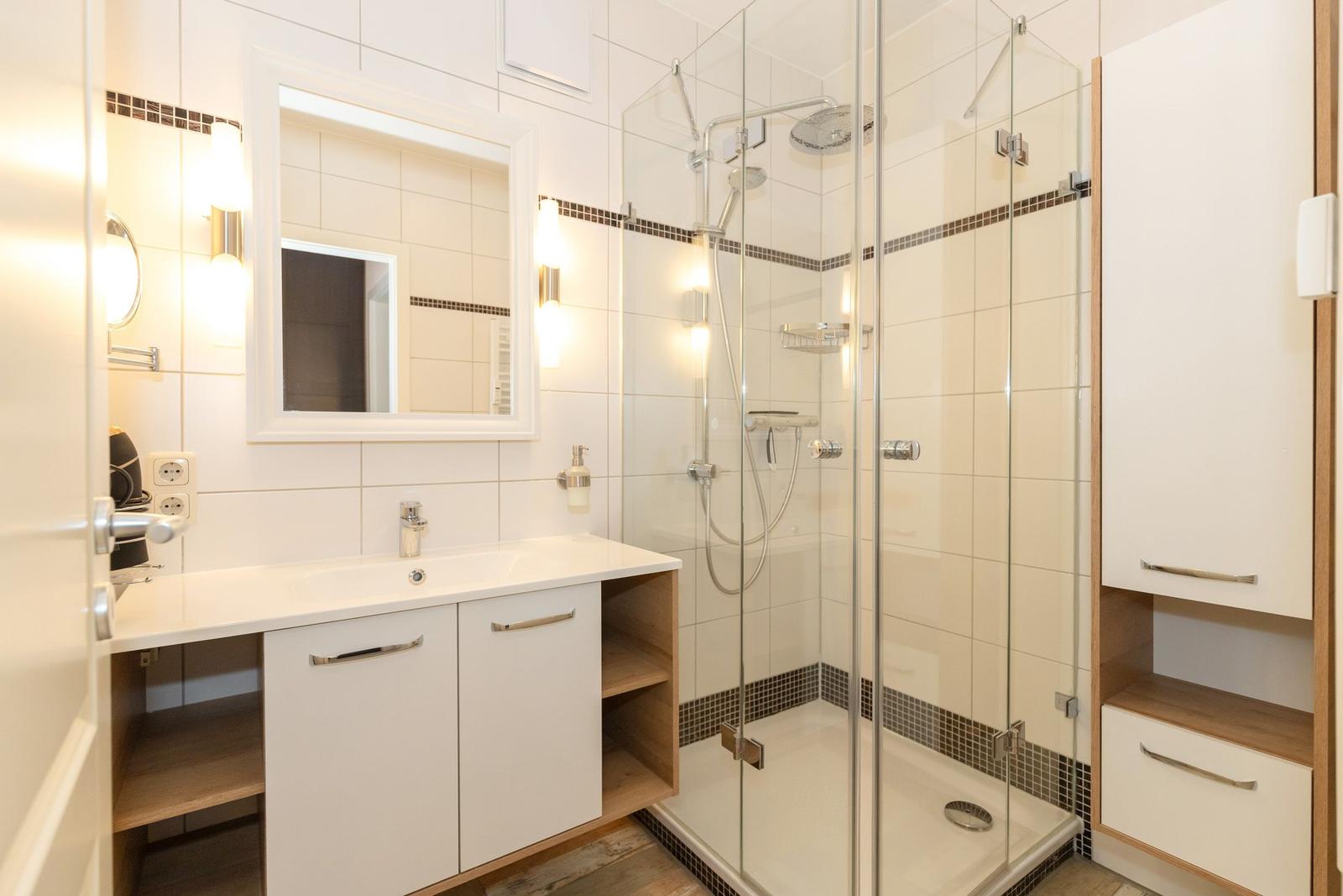 Badezimmer mit Dusche, Waschbecken und Spiegel