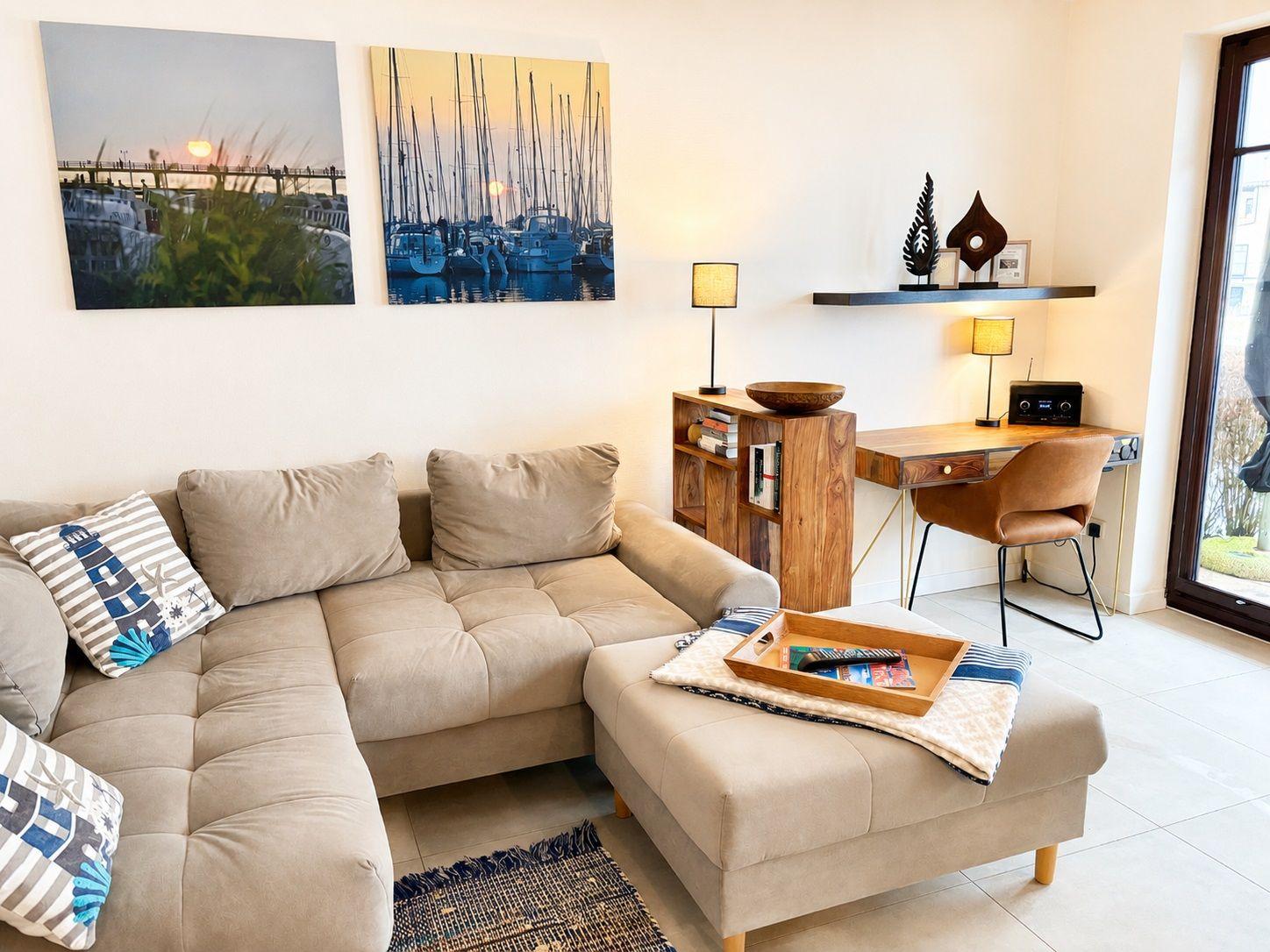 Wohnzimmer mit Sofa, Schreibtisch und Wandbildern