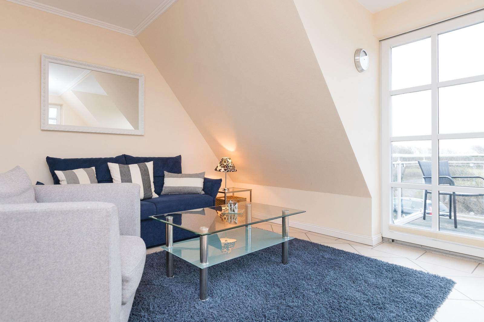 Wohnzimmer mit Sofa, Glas-Tisch und Balkontür