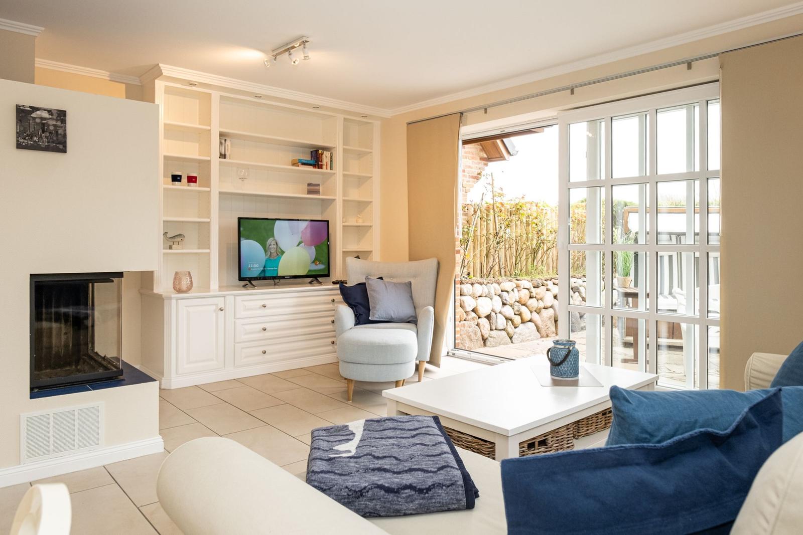 Wohnzimmer mit Kamin, TV und Blick auf den Garten.