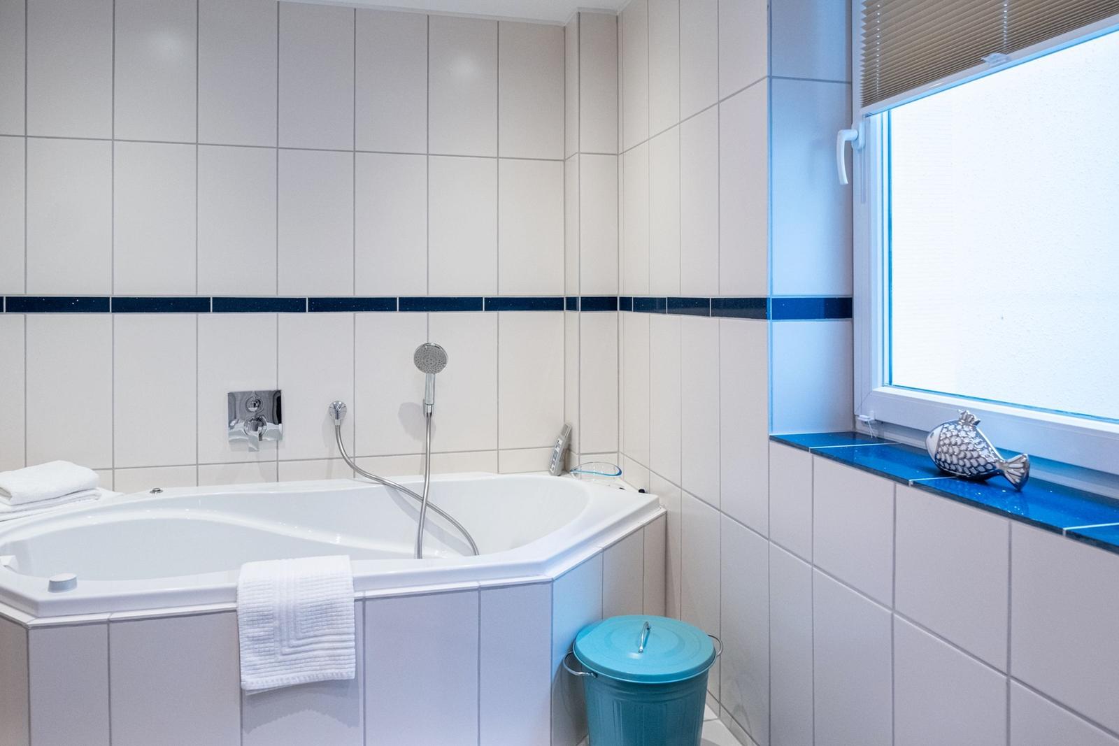 Bad mit Whirlpool, blauem Fensterbrett und Handdusche