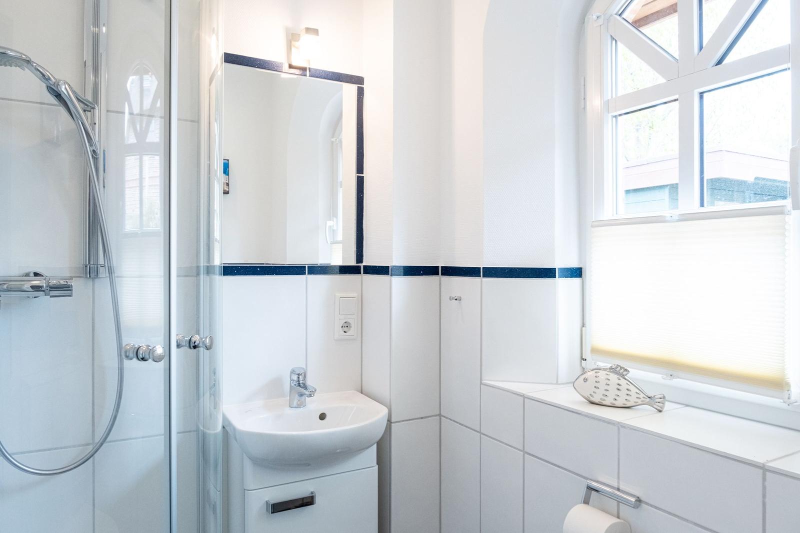 Badezimmer mit Dusche, Waschbecken und Fenster
