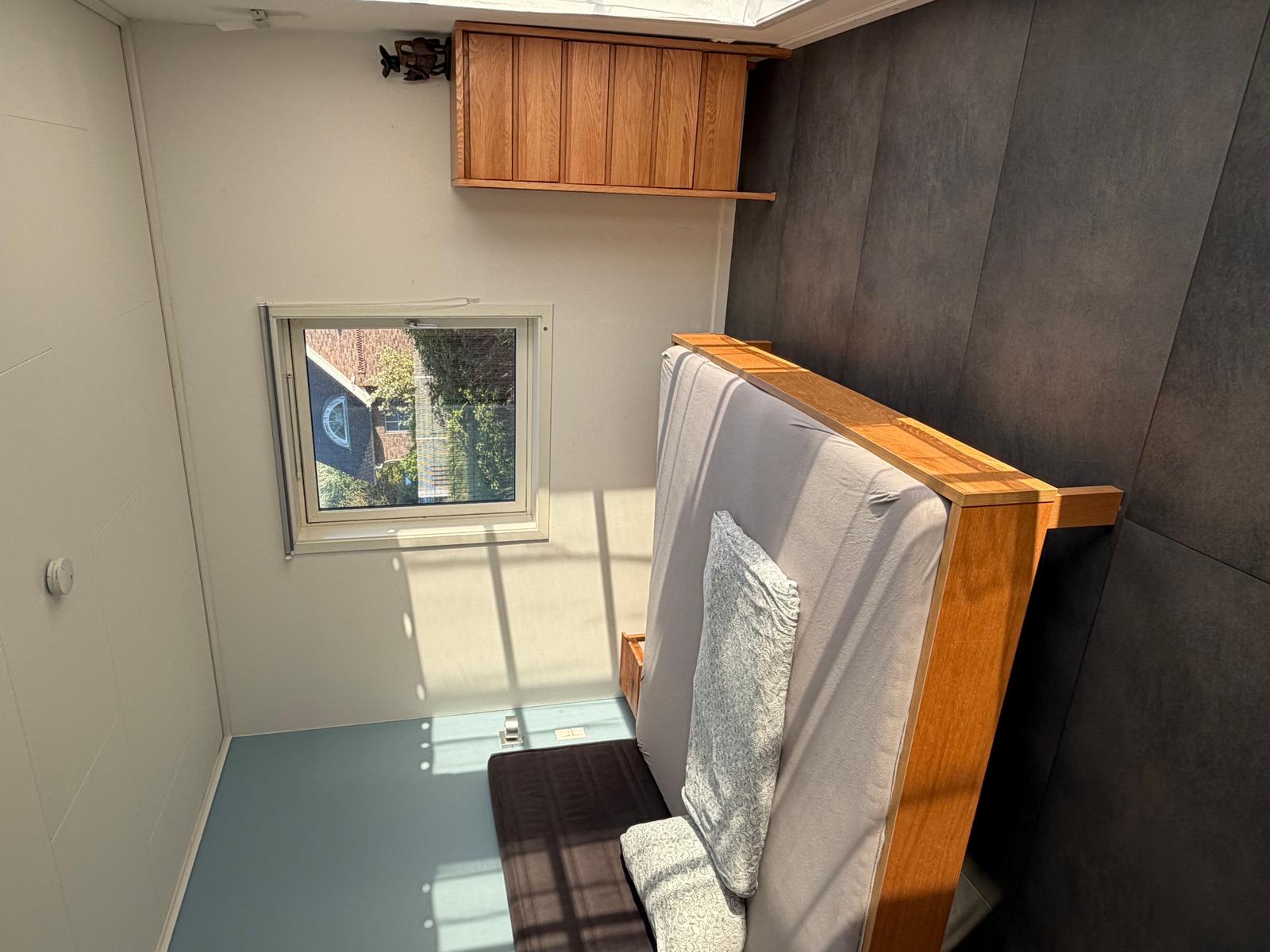 Schlafzimmer mit Bett, Fenster und Holzschränken