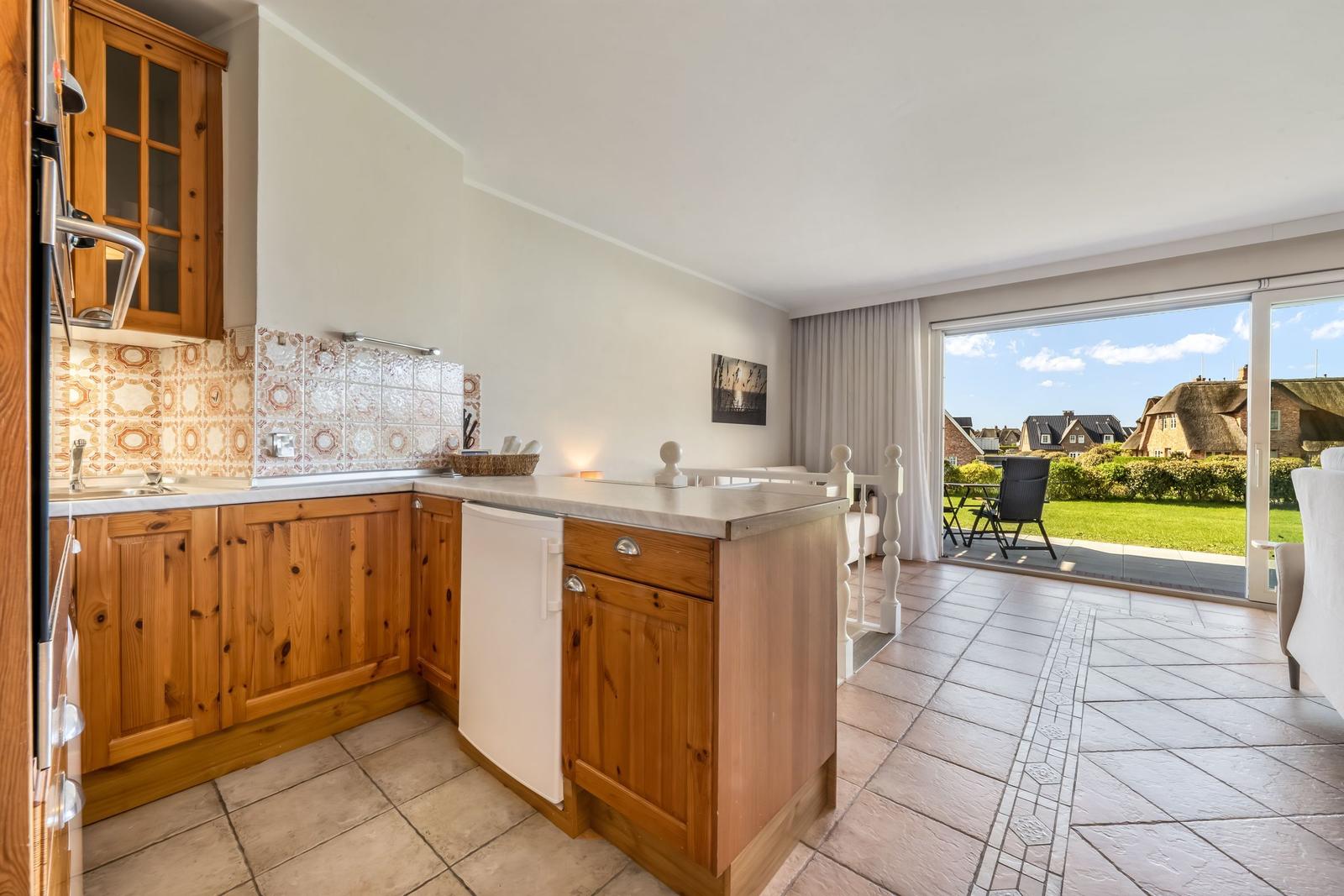 Kitchen with wooden cabinets and view of terrace with garden.