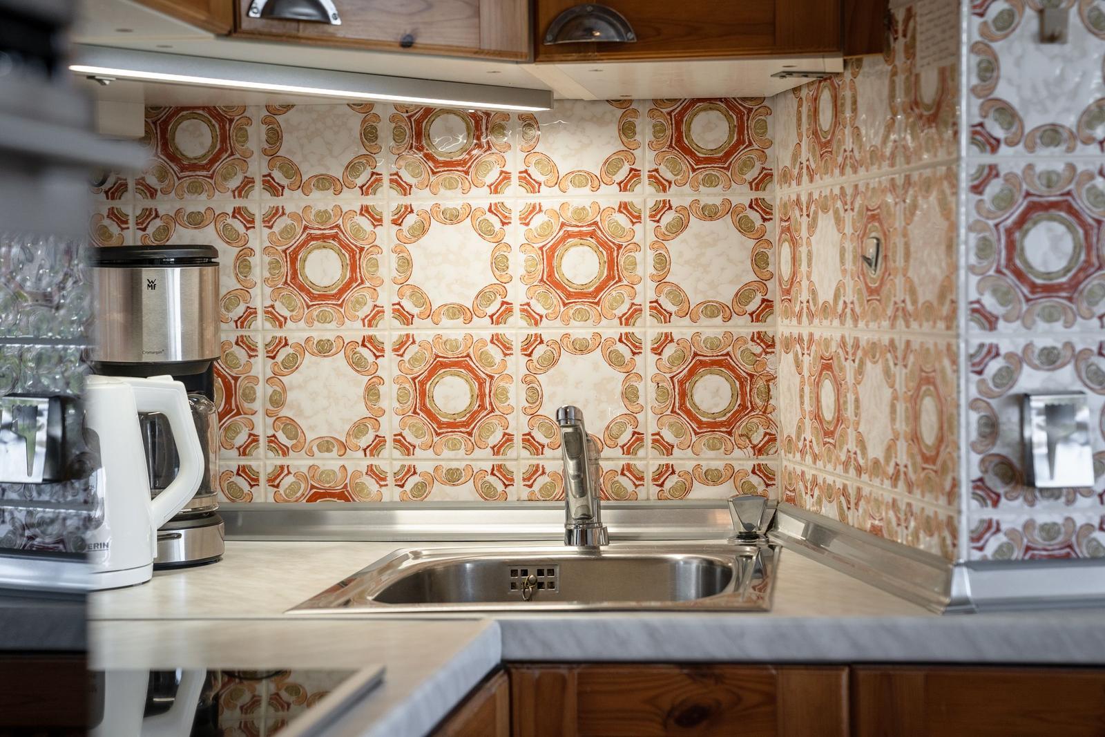 Kitchenette with mosaic backsplash, sink, and appliances.