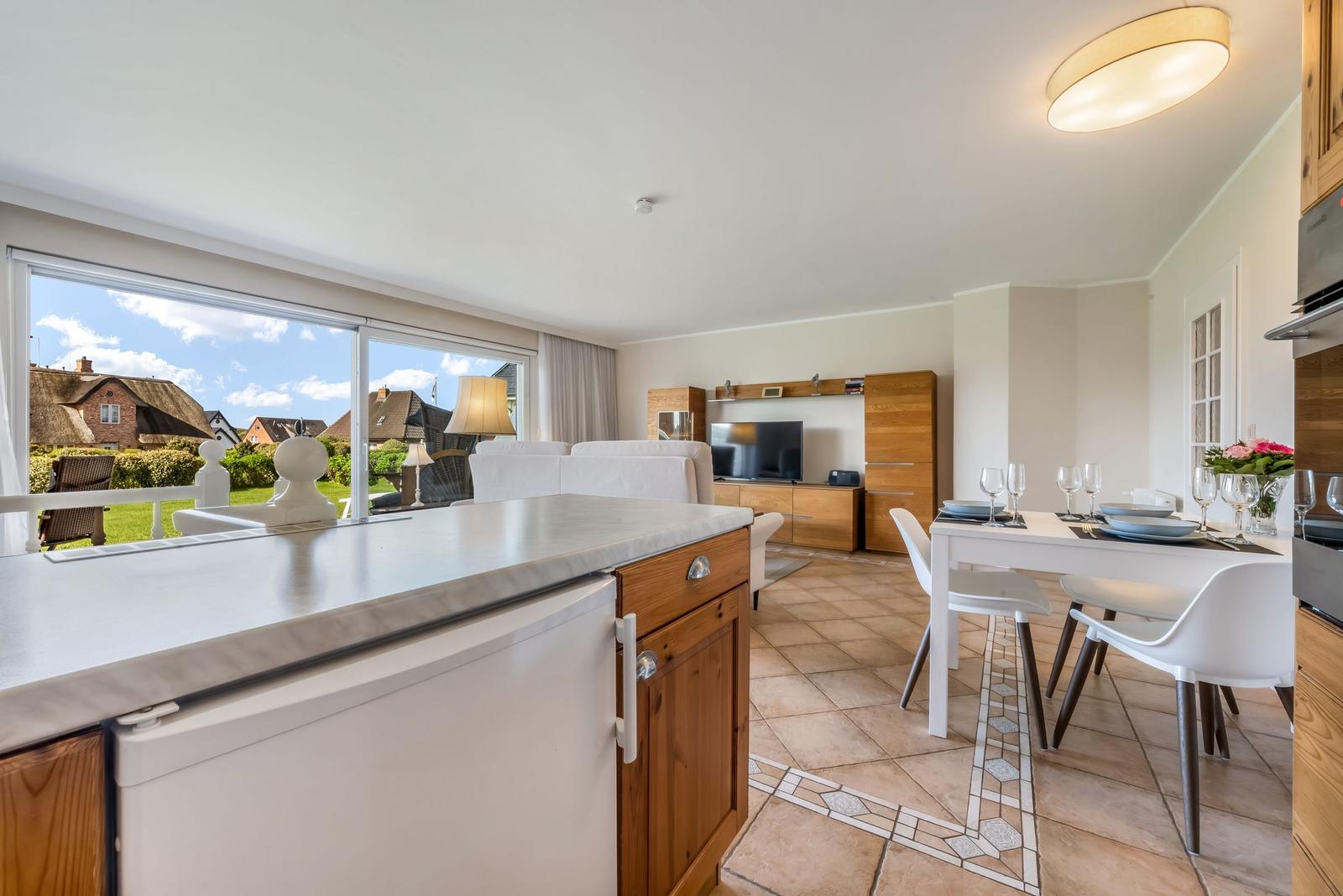 Kitchen-living area with dining table, TV, and garden view.
