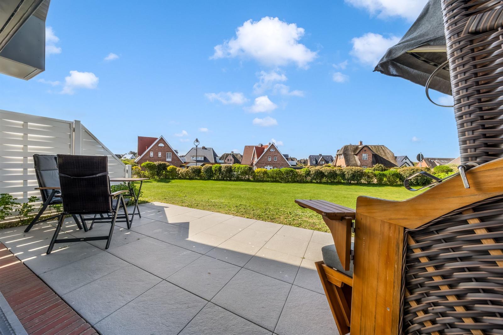 Terrace with garden view of traditional houses and green lawns under blue sky.