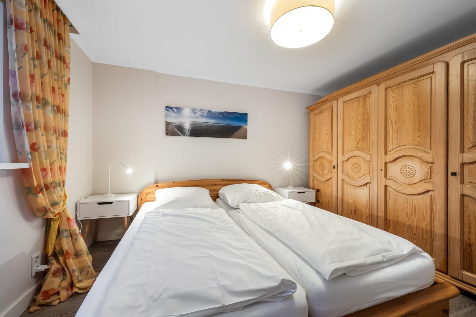 Bedroom with double bed, wooden wardrobe, and nightstands.