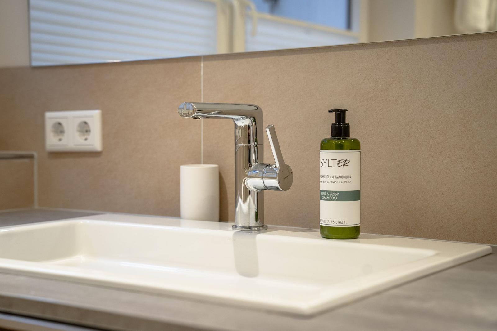 Sink with modern faucet and soap bottle.