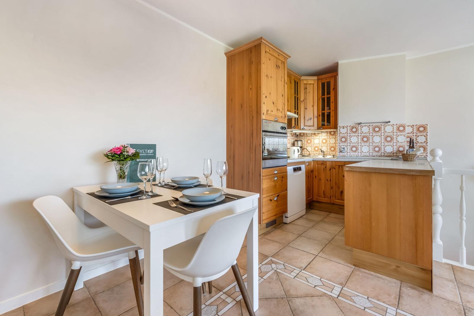 Dining area with table and chairs. Kitchen area with wooden cabinets and countertop.