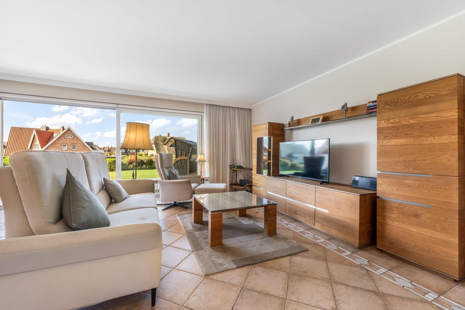 Living room with sofa, TV, and view of garden