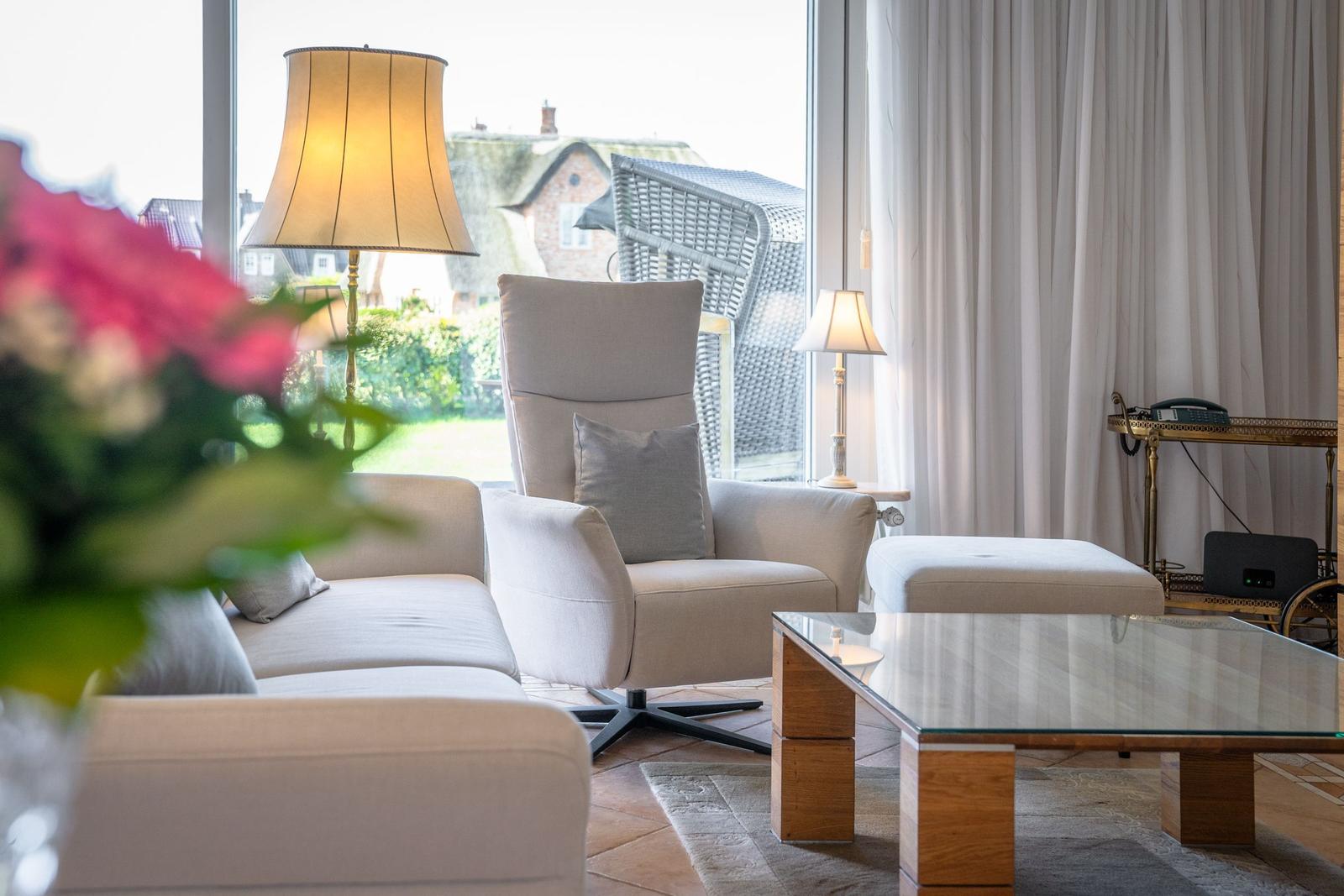 Living room with seating area, glass table, and garden view
