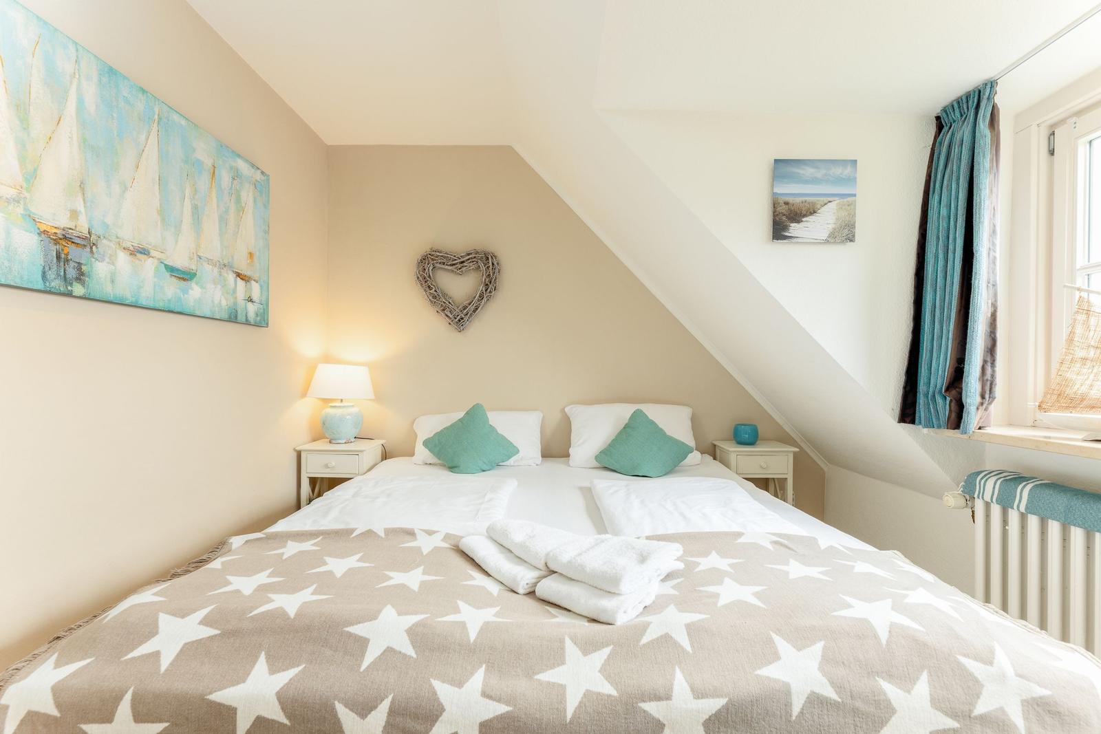 Schlafzimmer mit Dachschrägen, Bett mit Sternen-Decke und Wandbildern.