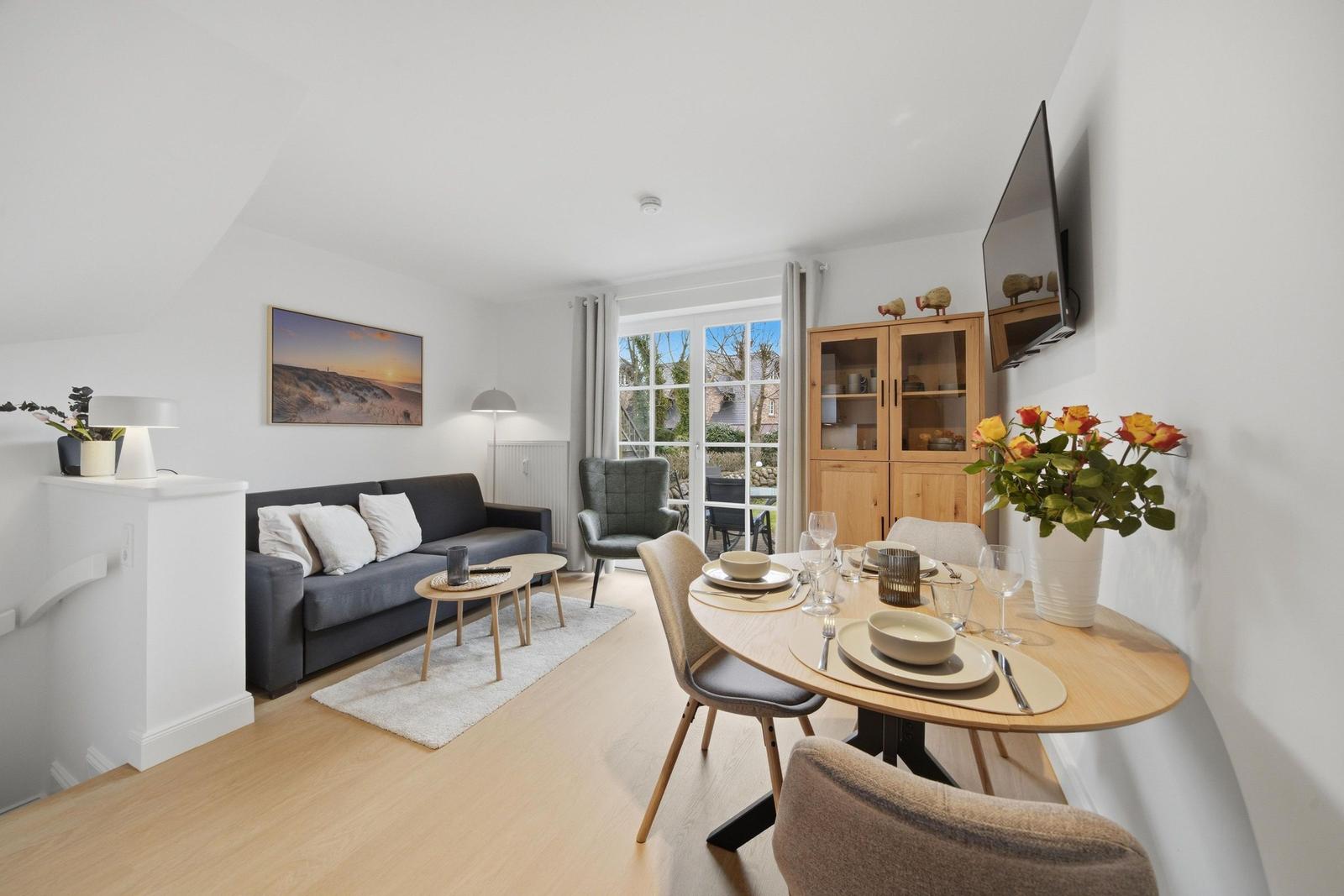 Living and dining area with sofa, table, and TV. Entrance to terrace.