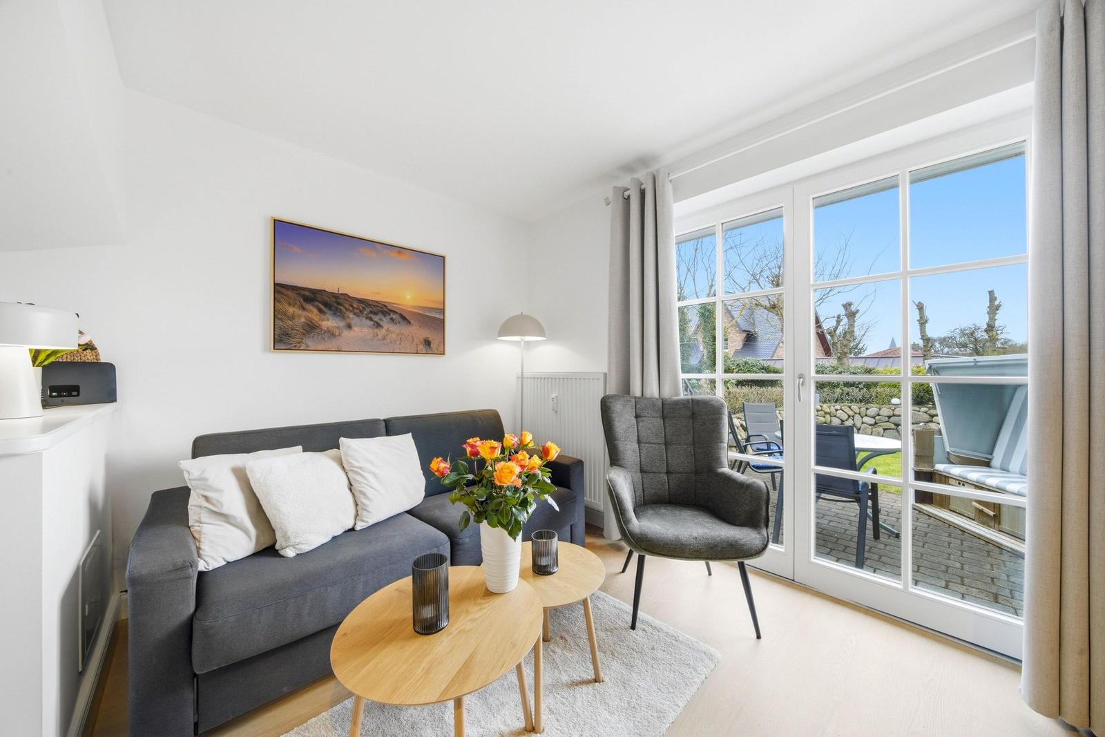 Living room with sofa, armchair, and view of terrace.