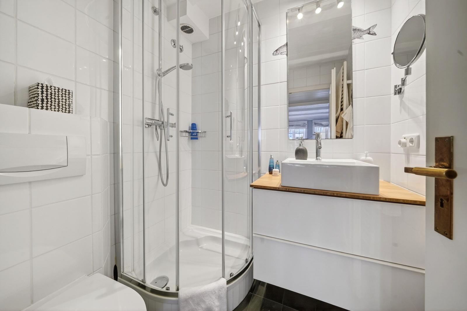 Badezimmer mit Dusche, Waschbecken und Spiegel.
