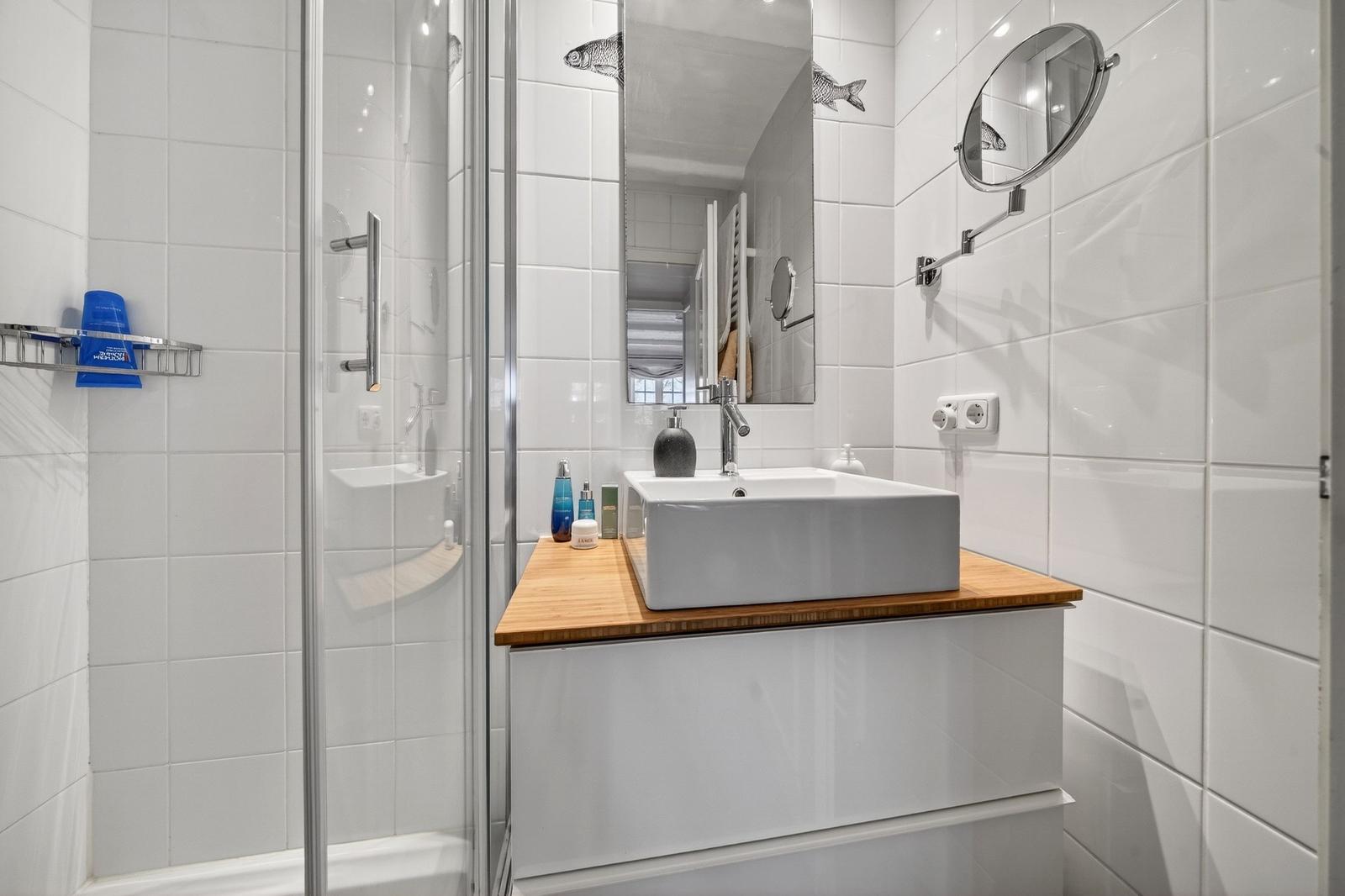 Badezimmer mit Dusche, Waschbecken und Spiegel an der Wand.
