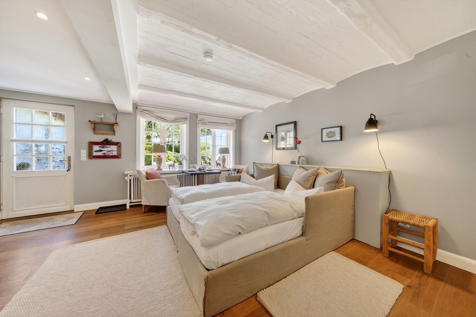 Schlafzimmer mit Doppelbett, Holzboden und weißen Balken an der Decke.